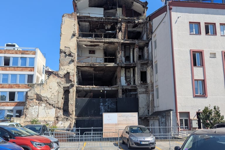 A multi-story bombed Radio Television ruins in Belgrade under a clear blue sky next to a parking lot