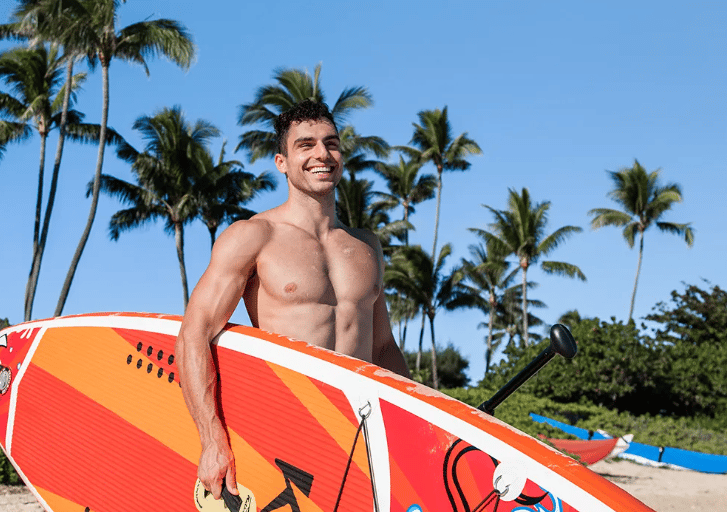 vyras nešasi irklentę, kuri yra ryškių spalvų orandžinė, 350 cm ilgio