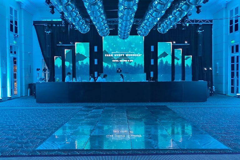 Escenario de evento con pantallas LED verticales, iluminación perimetral azul y pista de baile profe