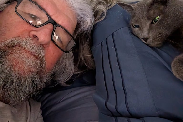 Greg Rowland and his cat, Big Bit laying in bed together.