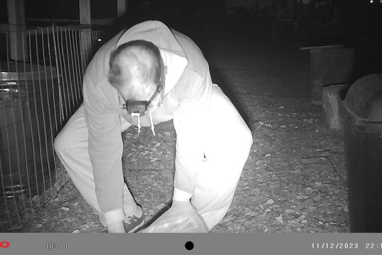 Martin picking up dead rat he shot.