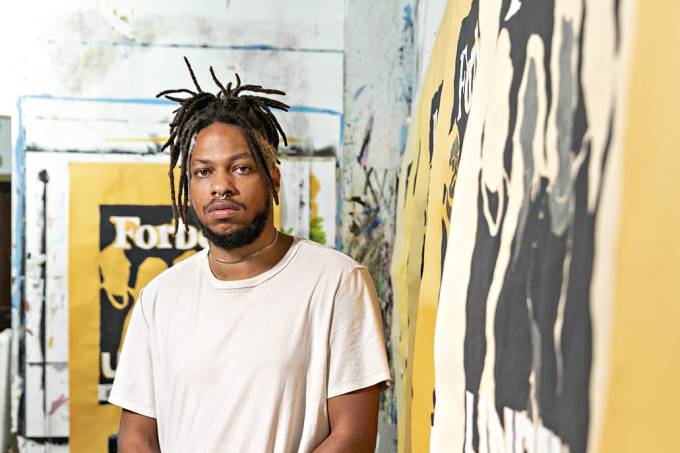 artista Maxwell Alexandre ao lado de suas obras