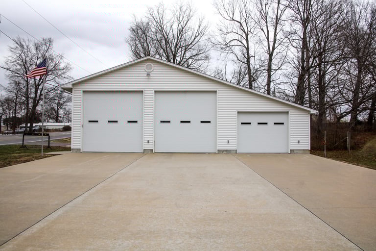 A fire station with 3 garage doors and a flag pole