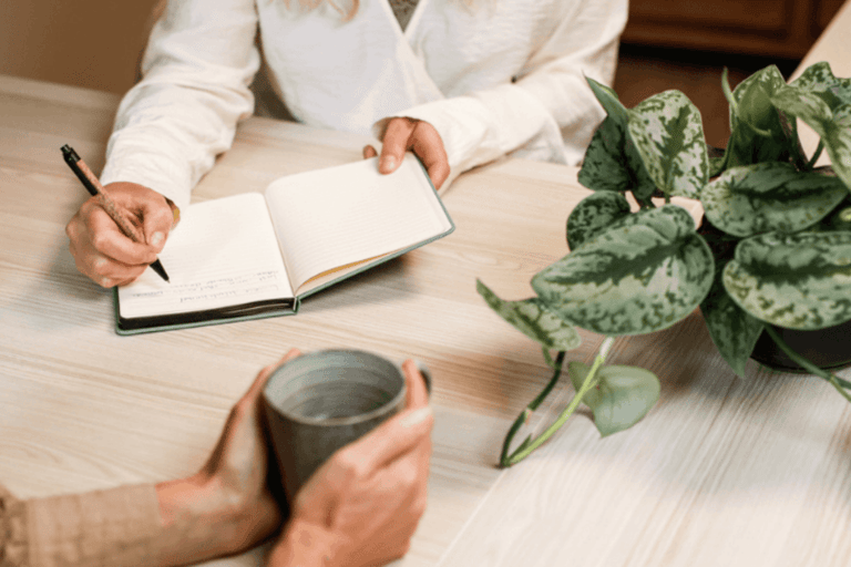 Jacquelien Noteert in haar notitieboek terwijl de klant met een kopje koffie in haar hand verteld