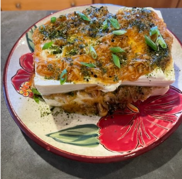 a plate with a slice of tofu with enoki mushrooms
