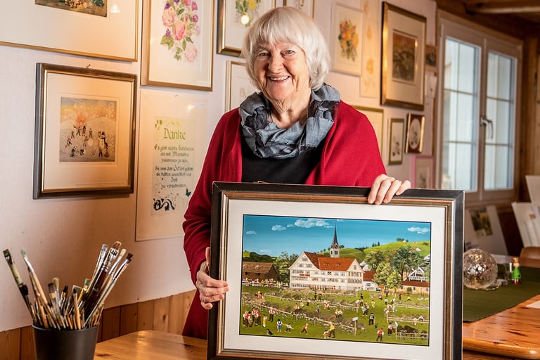 Eine Frau, die ein Bild eines Gemäldes eines Hauses hält
