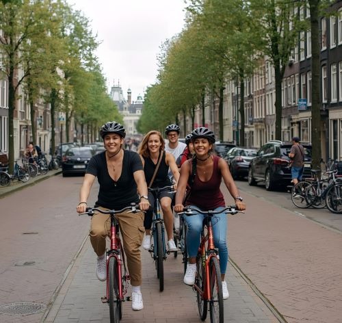 A group of smiling tourists wearing helmets while cycling on a city street in Amsterdam.