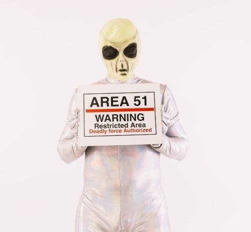 a man in a silver suit and sunglasses holding a sign that says area 515