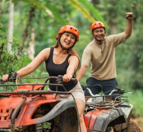 a man and woman riding on atvs in the woods