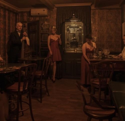 a man in a suit and tie is standing in a 19th century brothel