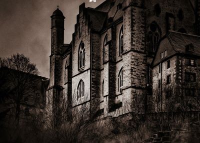 a creepy looking building with a clock tower in the background