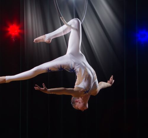a woman in white and blue outfit performing a trick on a hoop