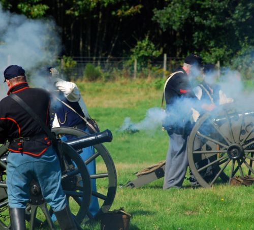 a group of men in uniform uniforms standing around a cannon
