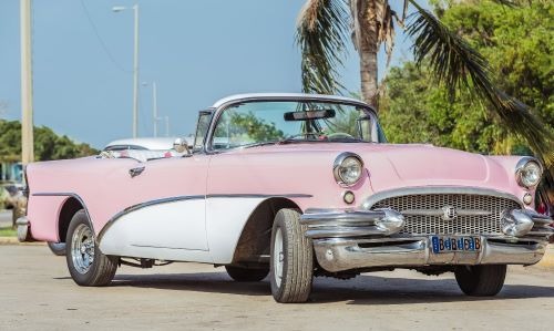 a classic pink car parked in a parking lot
