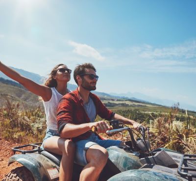 a man and woman riding on a quad - bike