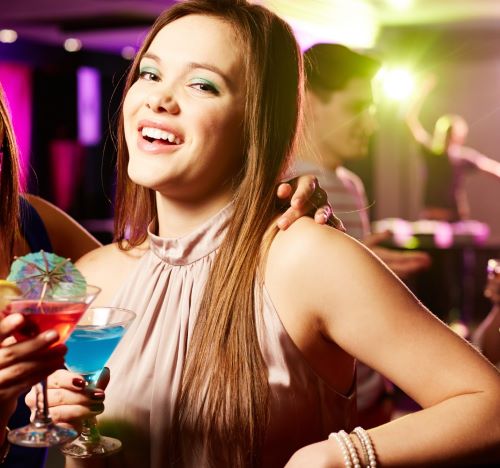 two women are smiling and having fun at a cocktail party