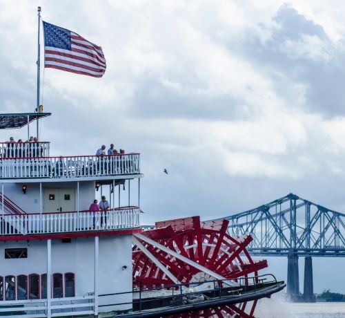 a paddle boat with a flag on it on the mississipi river