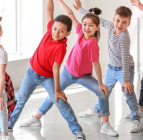 Diverse group of children in a dance class practicing synchronized moves in a bright studio.