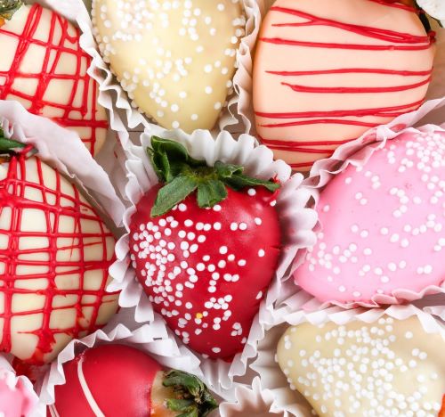 a box of chocolate covered strawberries with white and red sprinkles