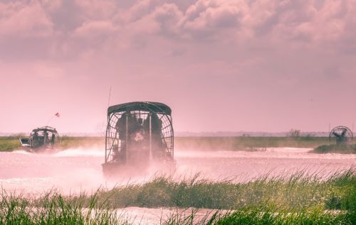 a airboat traveling through the water with a boat in the background