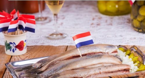 a tray of herring fish with a dutch flag on it