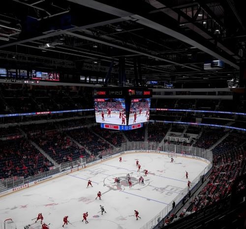 a hockey game in a stadium with a large screen