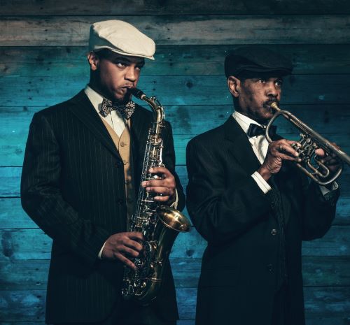 a man in a suit and hat playing the saxophone