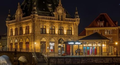 a luxury historical hotel building with a clock tower and a bridge over water
