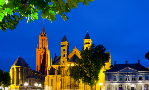 Illuminated Basilica of Saint Servatius and Saint John's Church at night in Maastricht.