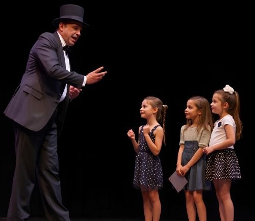 a magician in a suit and tie standing on stage