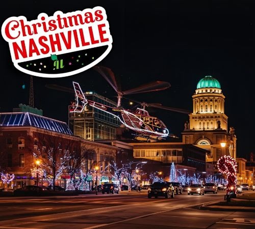 a helicopter flying over a city street with christmas lights
