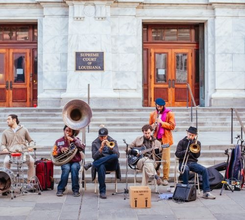 a group of musicians playing instruments in front of a building  in New Orleans