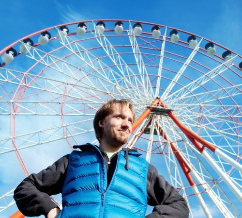 a man standing in front of a ferris wheel