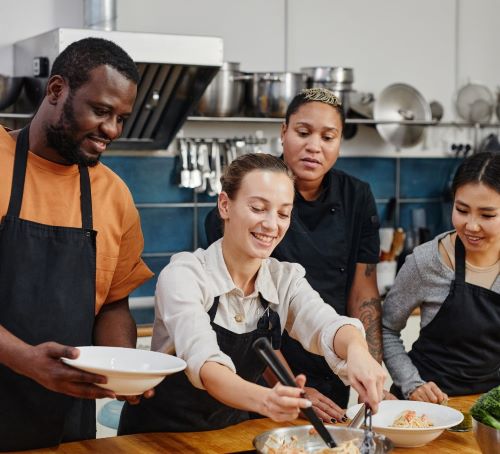 a group of people standing around a table with plates of food