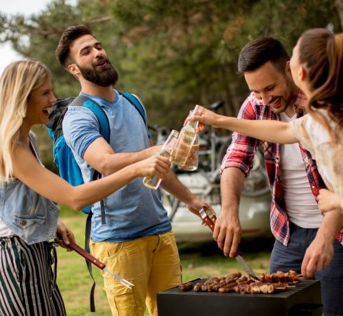 a group of people standing around a grill/bbq