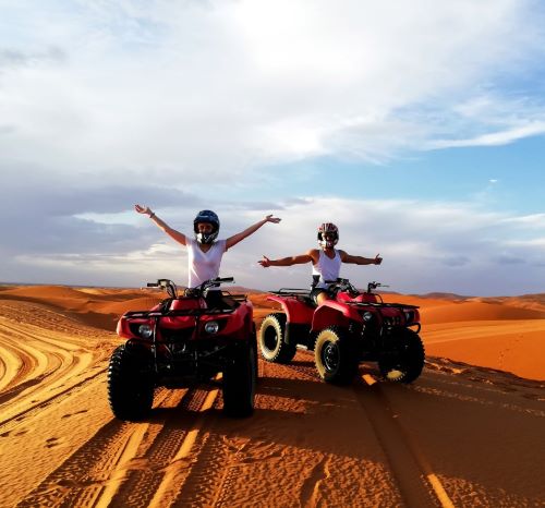 two people riding quad - atvs in the desert