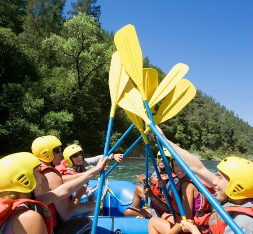 Raft navigating Class III rapids on the turbulent Ocoee River with spray flying.