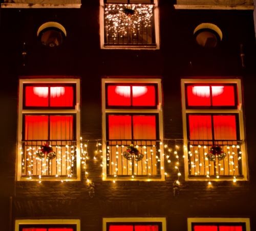 Traditional Dutch building facade at night decorated with glowing Christmas lights and festive ornaments.