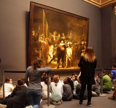 rembrandt painting - a group of people sitting on the ground in a museum