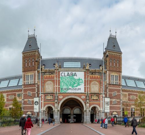 The Rijksmuseum in Amsterdam featuring the Clara rhinoceros exhibition banner on its historic facade.
