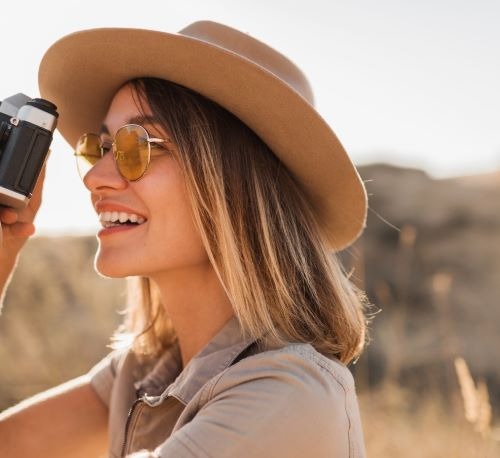 a woman in a hat and sunglasses is taking a picture of wildlife