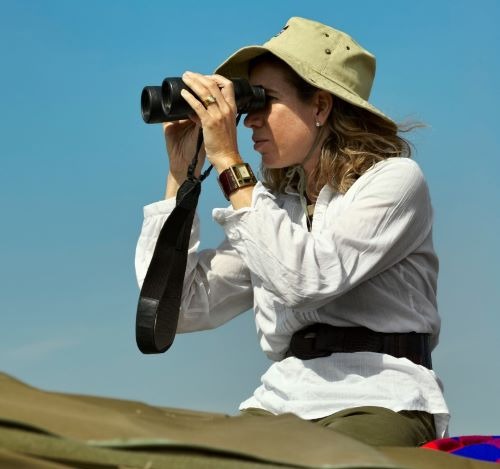a woman looking through binoculars for wildlife on a safari