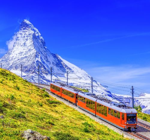 a train traveling down a mountain with a mountain in the background
