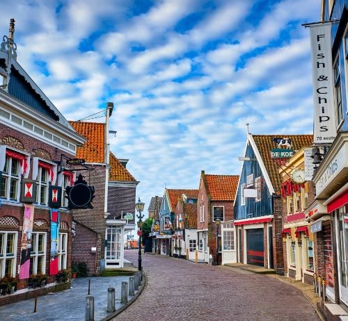 Charming cobblestone street in Volendam, Netherlands, with traditional Dutch architecture and fish and chips shops.