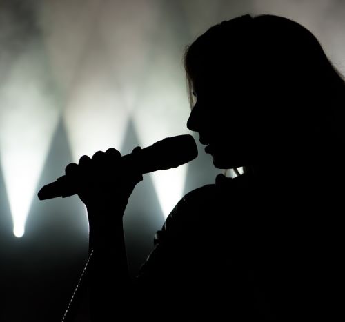 a woman singing into a microphone in front of a stage