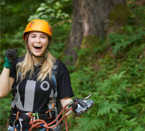 a woman in a helmet and safety gear on a zipline