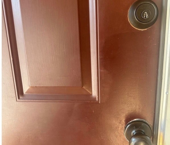 Red home door with deadbolt and knob representing residential locksmith services in Candler, NC for rekeying & smart locks
