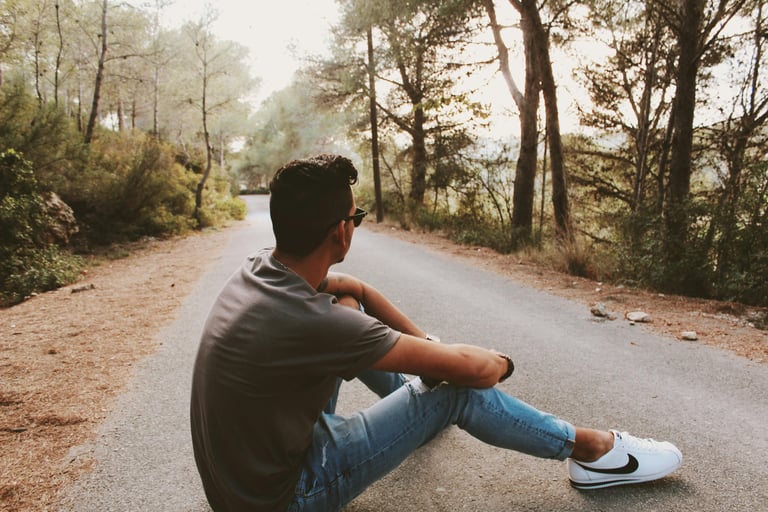 Guy sitting on a road in a forest