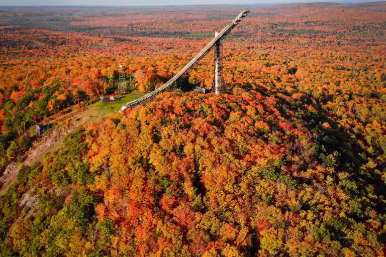 Tall Copper Peak ski jump structure in Ironwood, Michigan, surrounded by brilliant autumn trees.