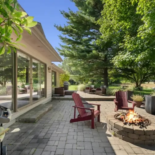 a patio with a fire pit and chairs
